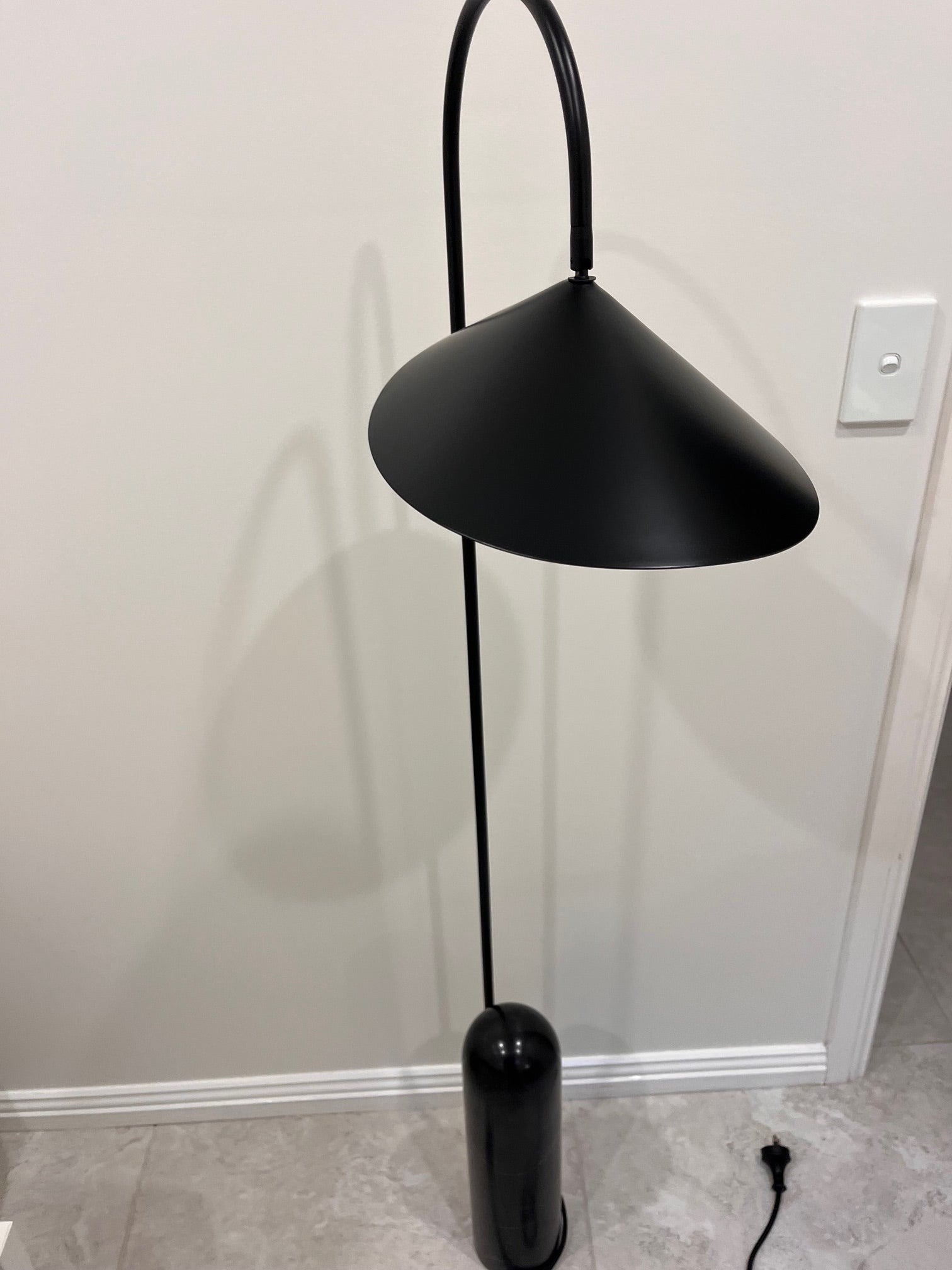Black floor lamp against a white wall