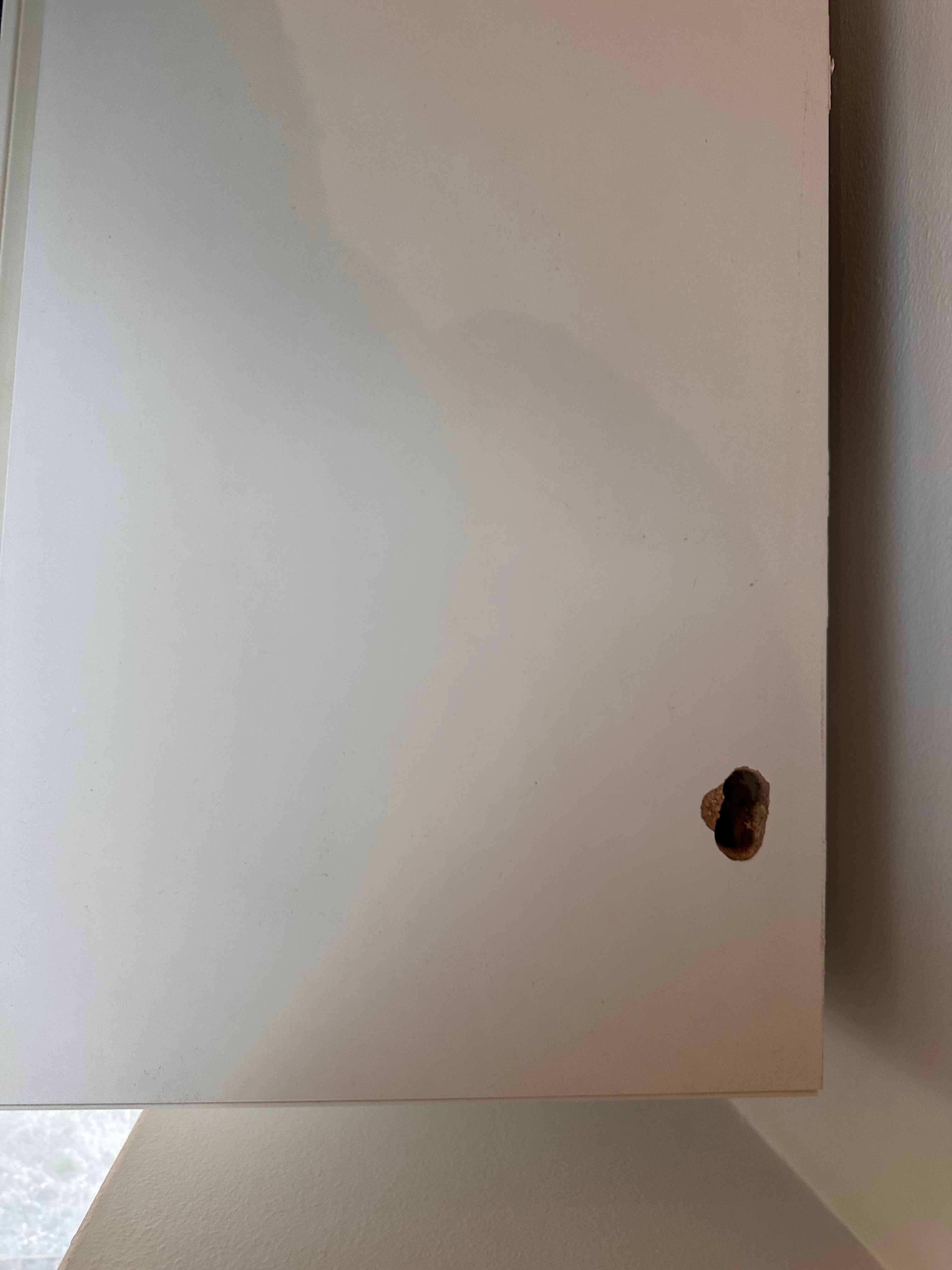 White cabinet with a hole in the wall behind it
