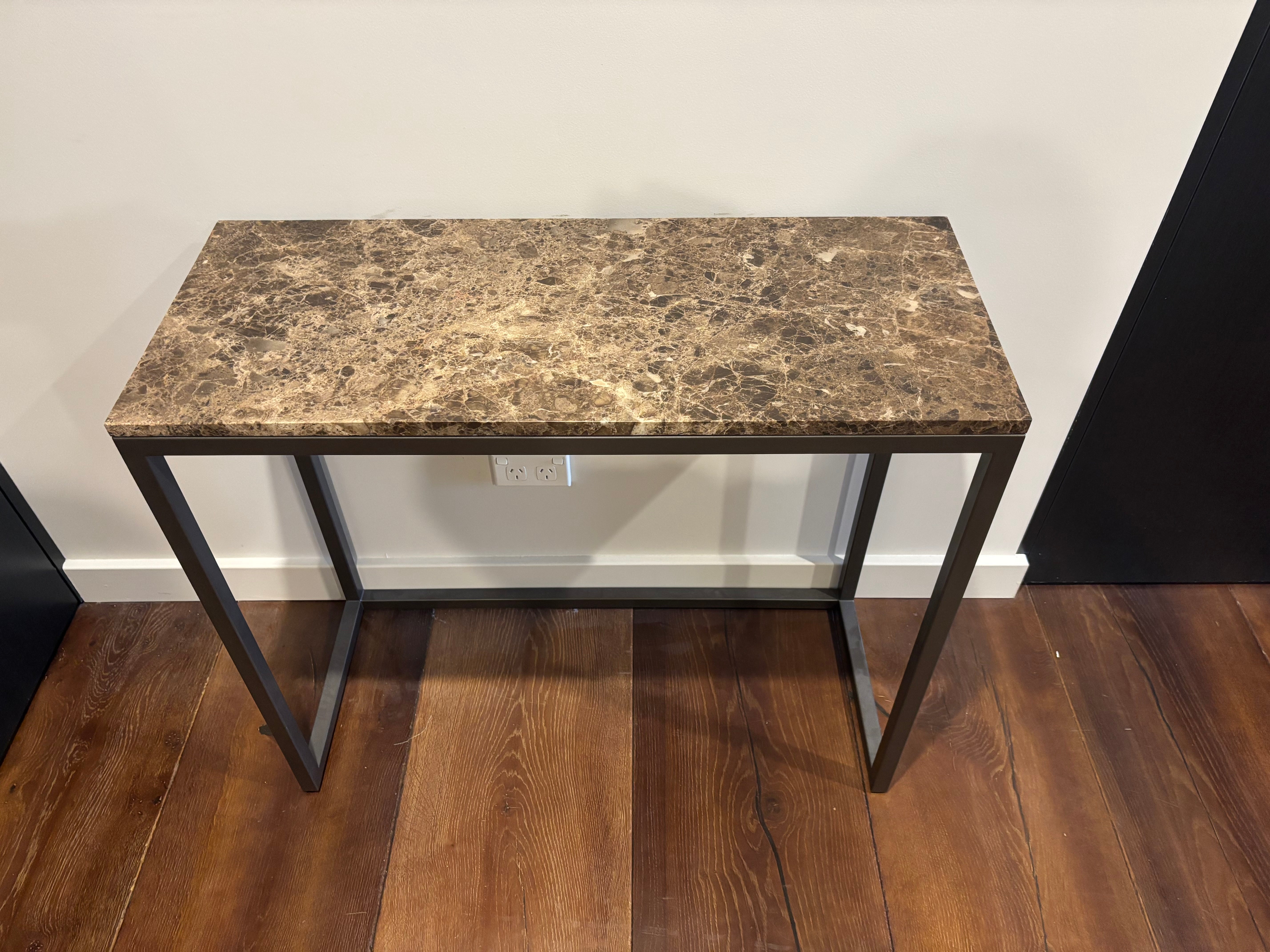 Small table with a marble-like top and metal legs on a wooden floor.