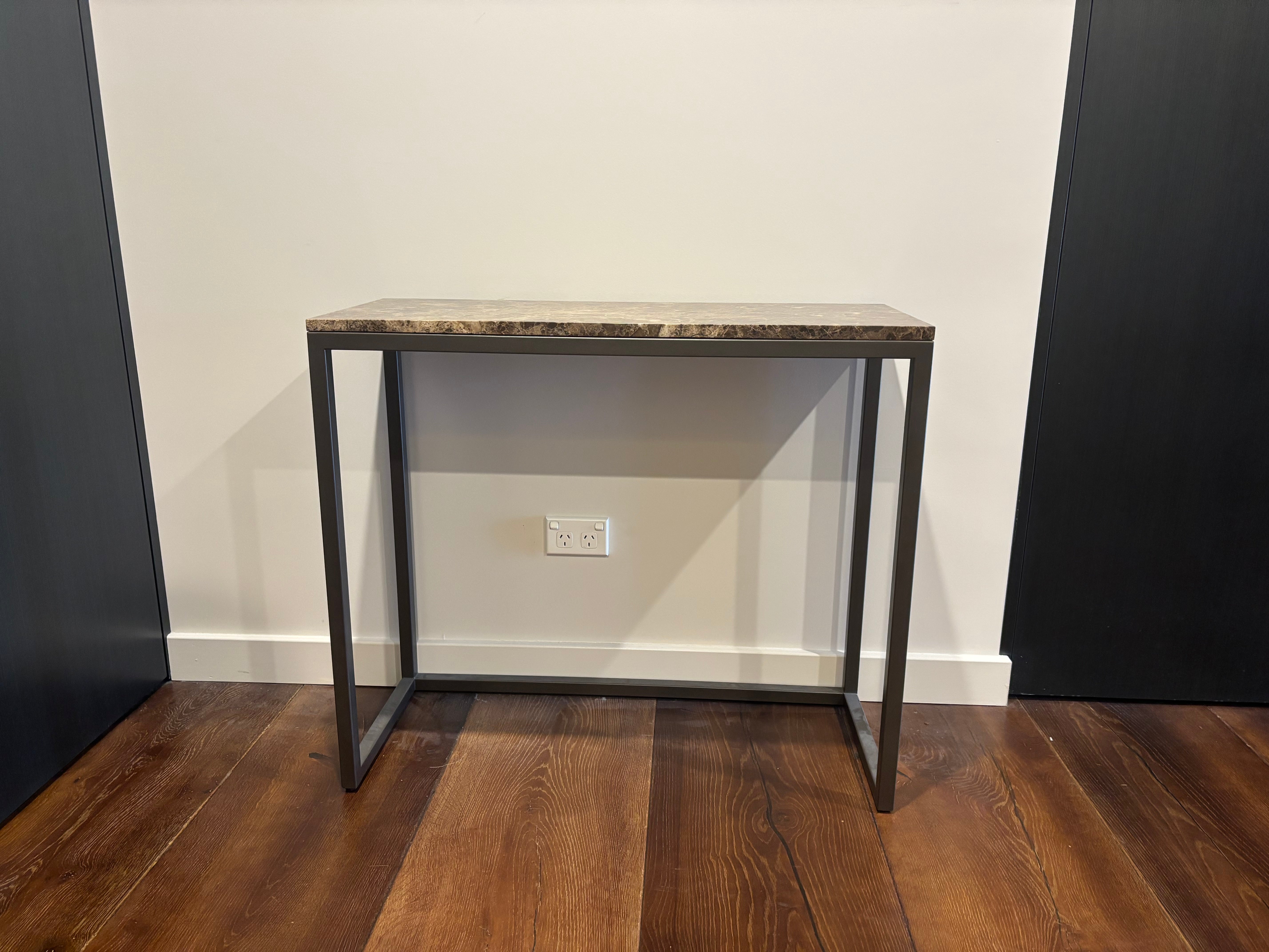 Console table with marble top and metal frame against a white wall.