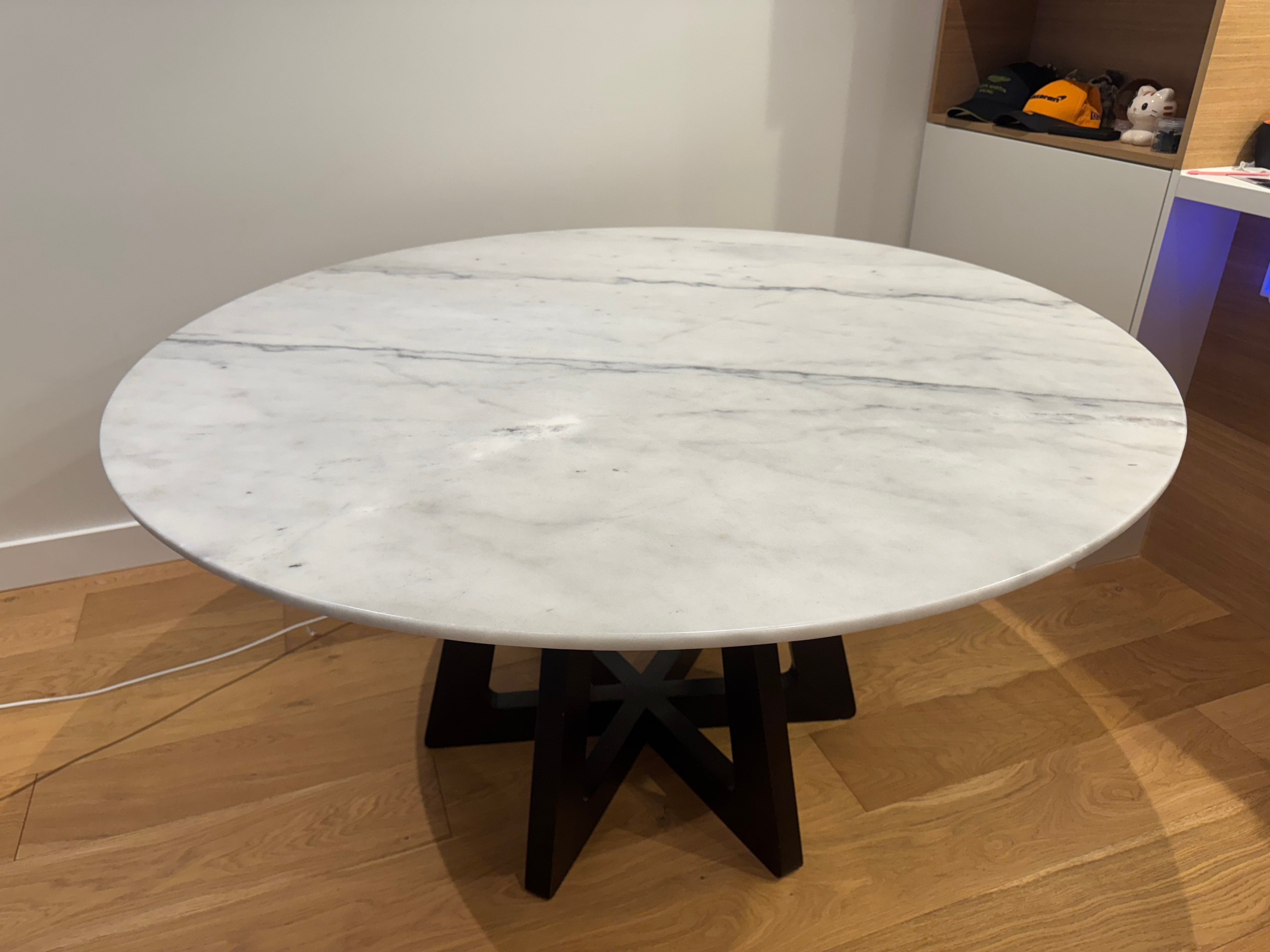 Round marble table with black base on a wooden floor