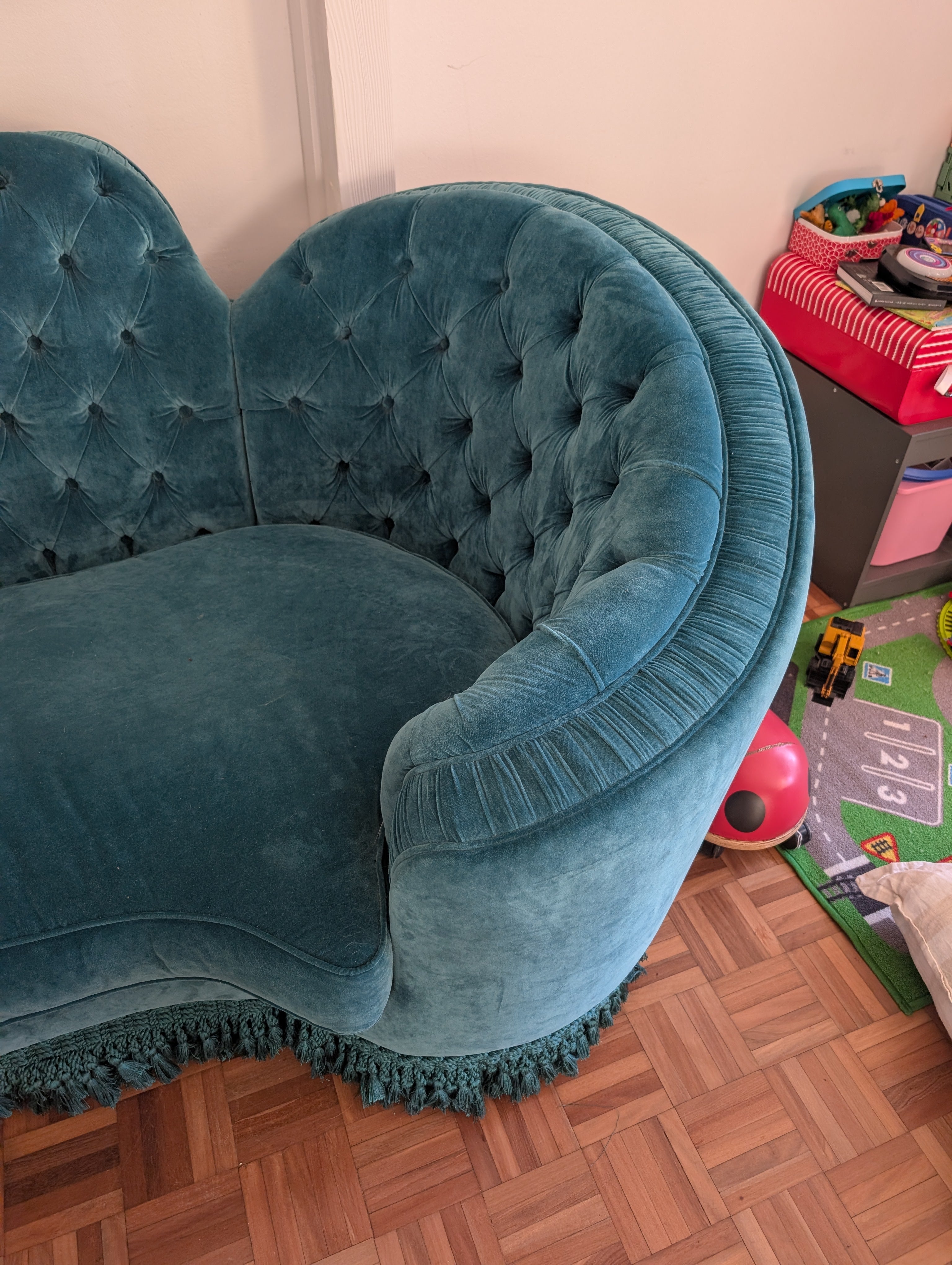 Blue velvet chair in a room with toys on the floor