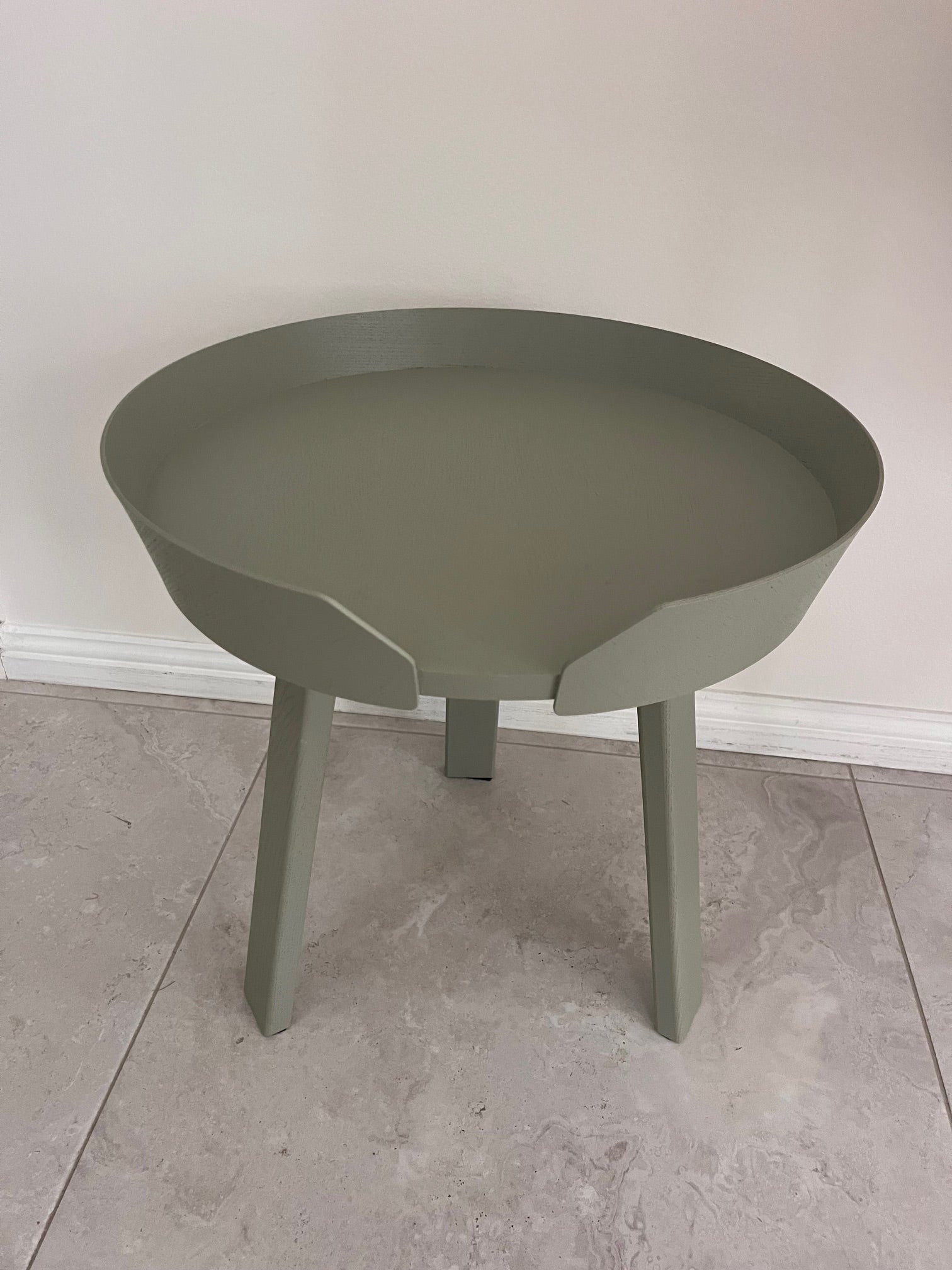 Green side table on a tiled floor with a neutral wall background