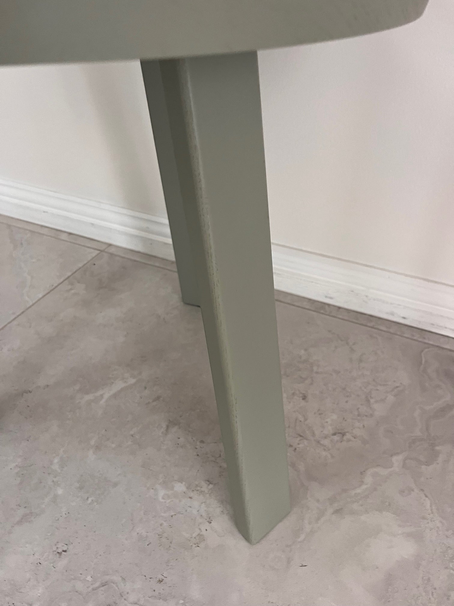 Close-up of a gray table leg on a tiled floor