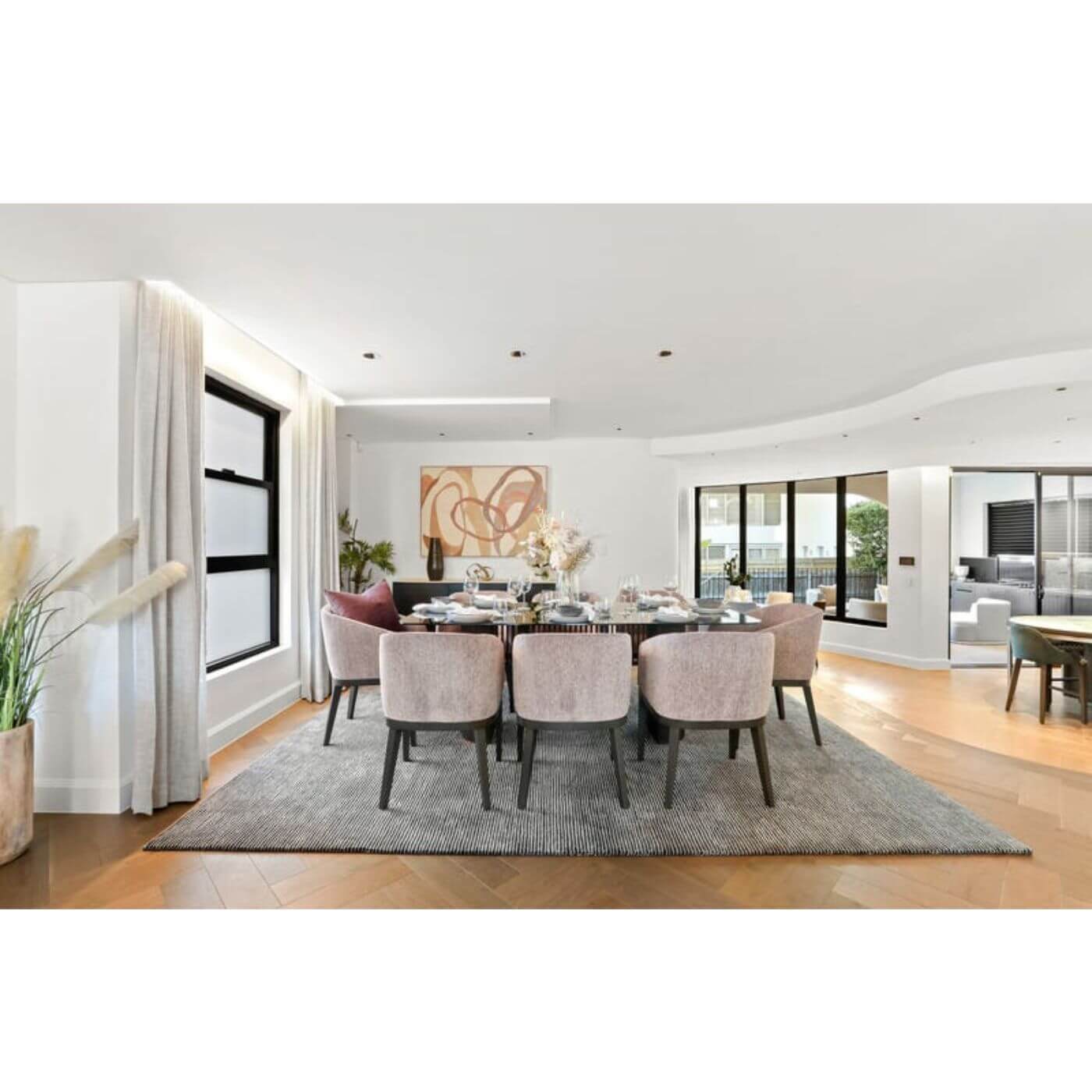 Modern dining room with a large table and chairs in a well-lit home.