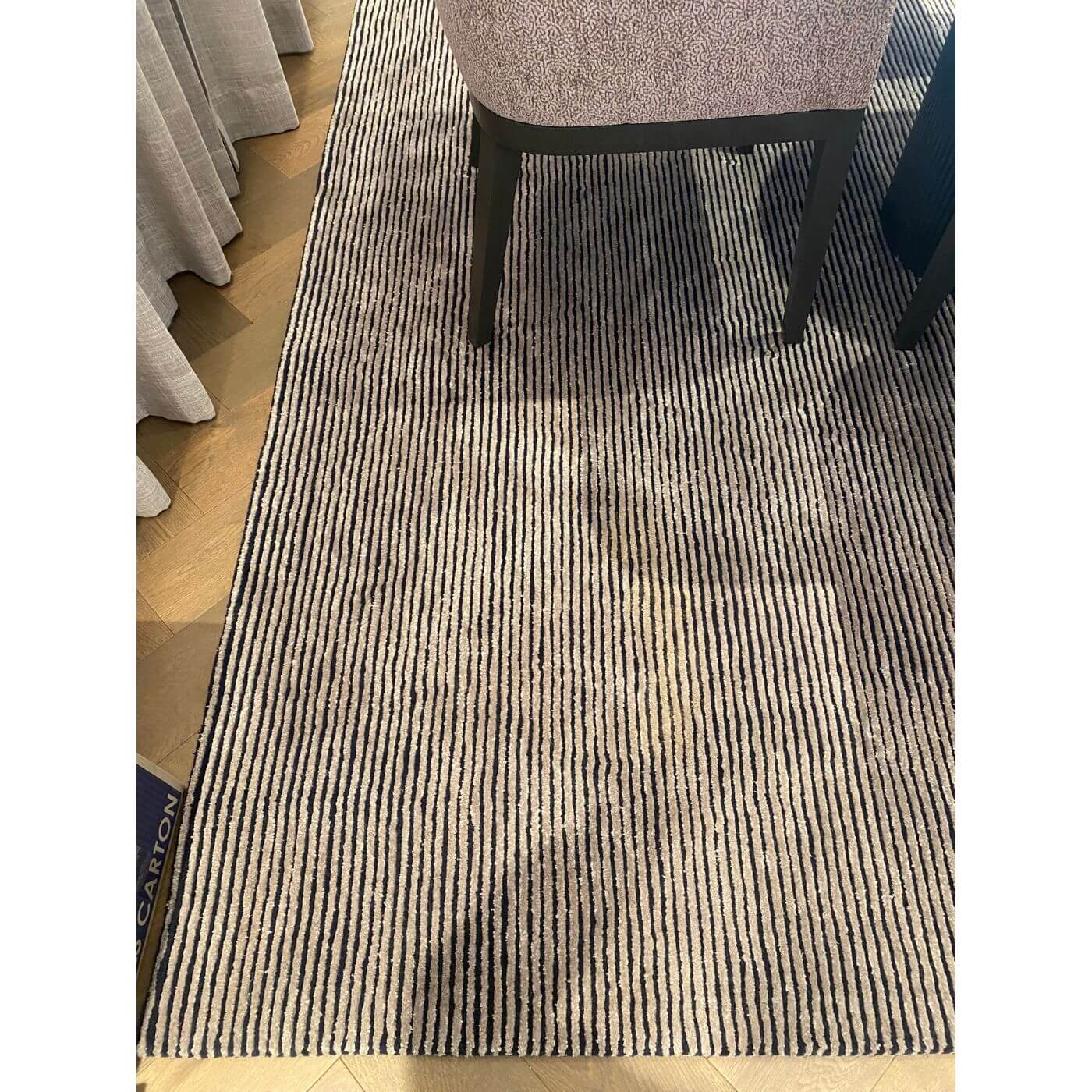 Striped rug on a wooden floor with a chair partially visible