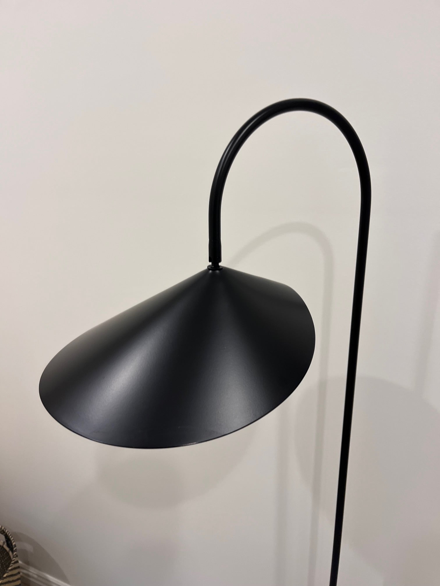 Black floor lamp with curved design against a white wall