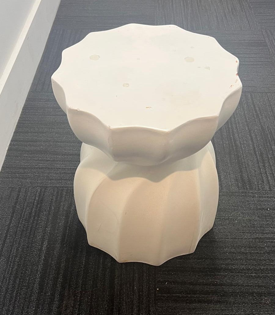 White geometric-shaped stool on a dark textured floor