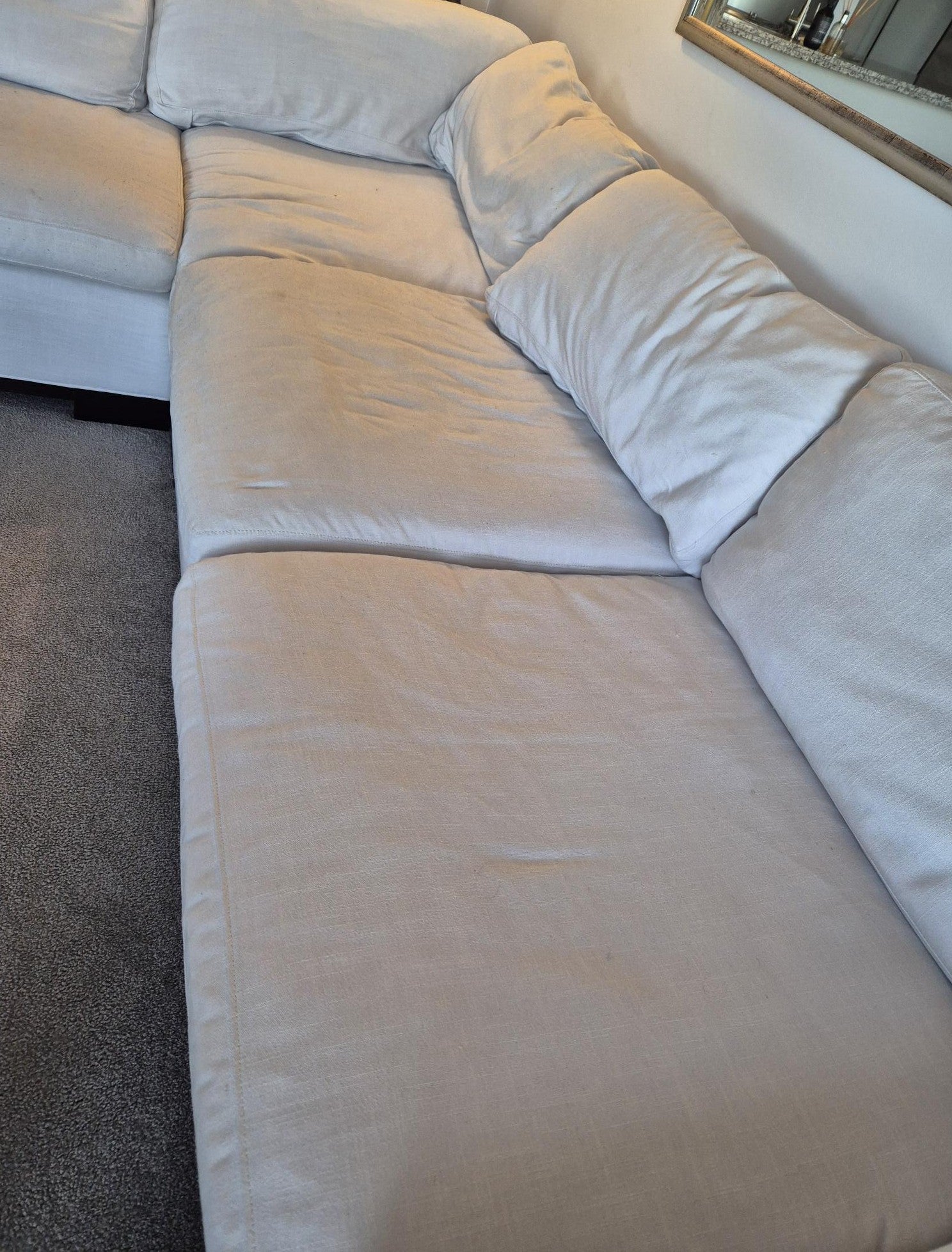 Beige sectional sofa with visible wear and tear in a room setting.
