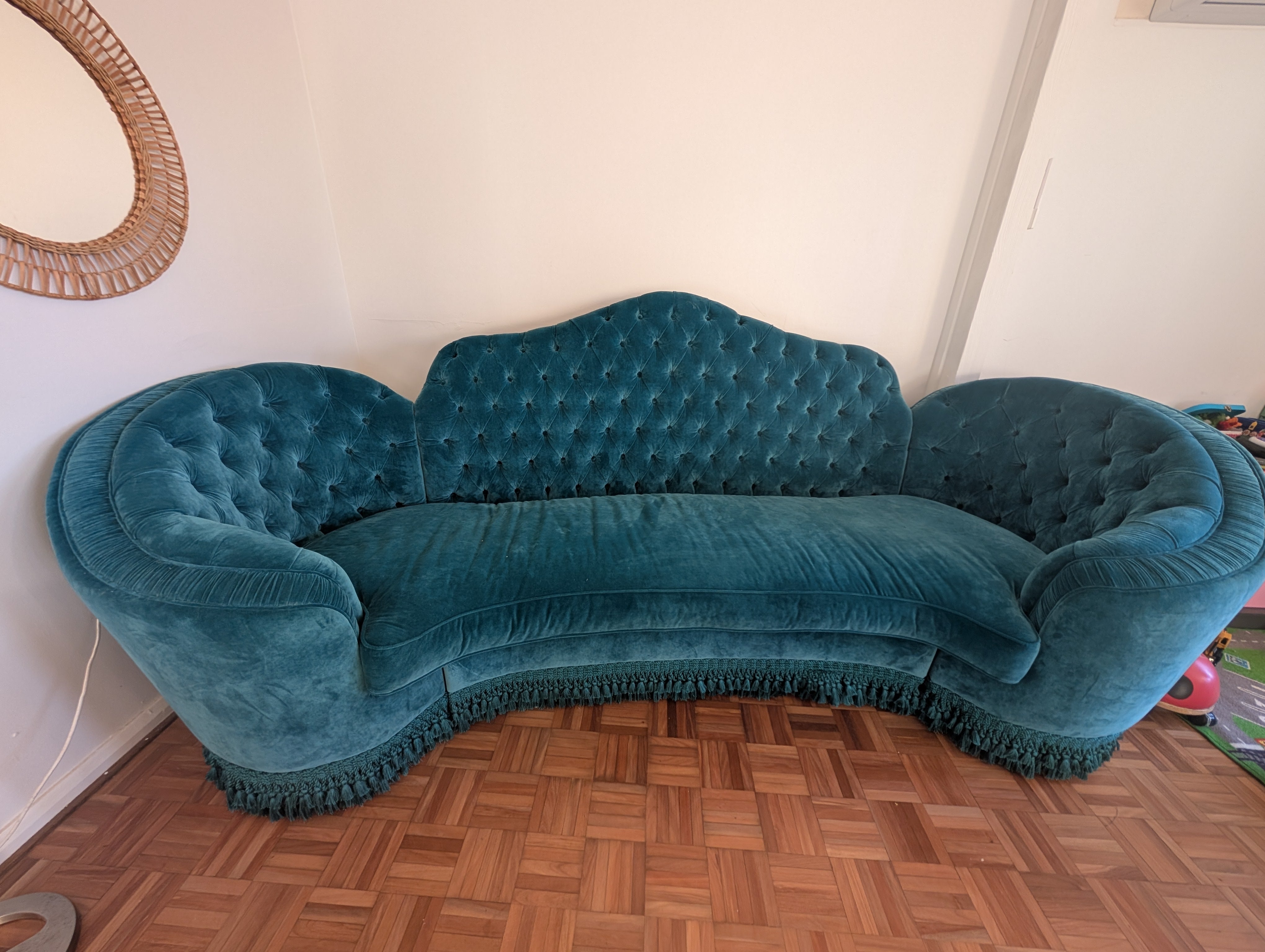 Blue tufted sofa on a wooden floor with a white wall background