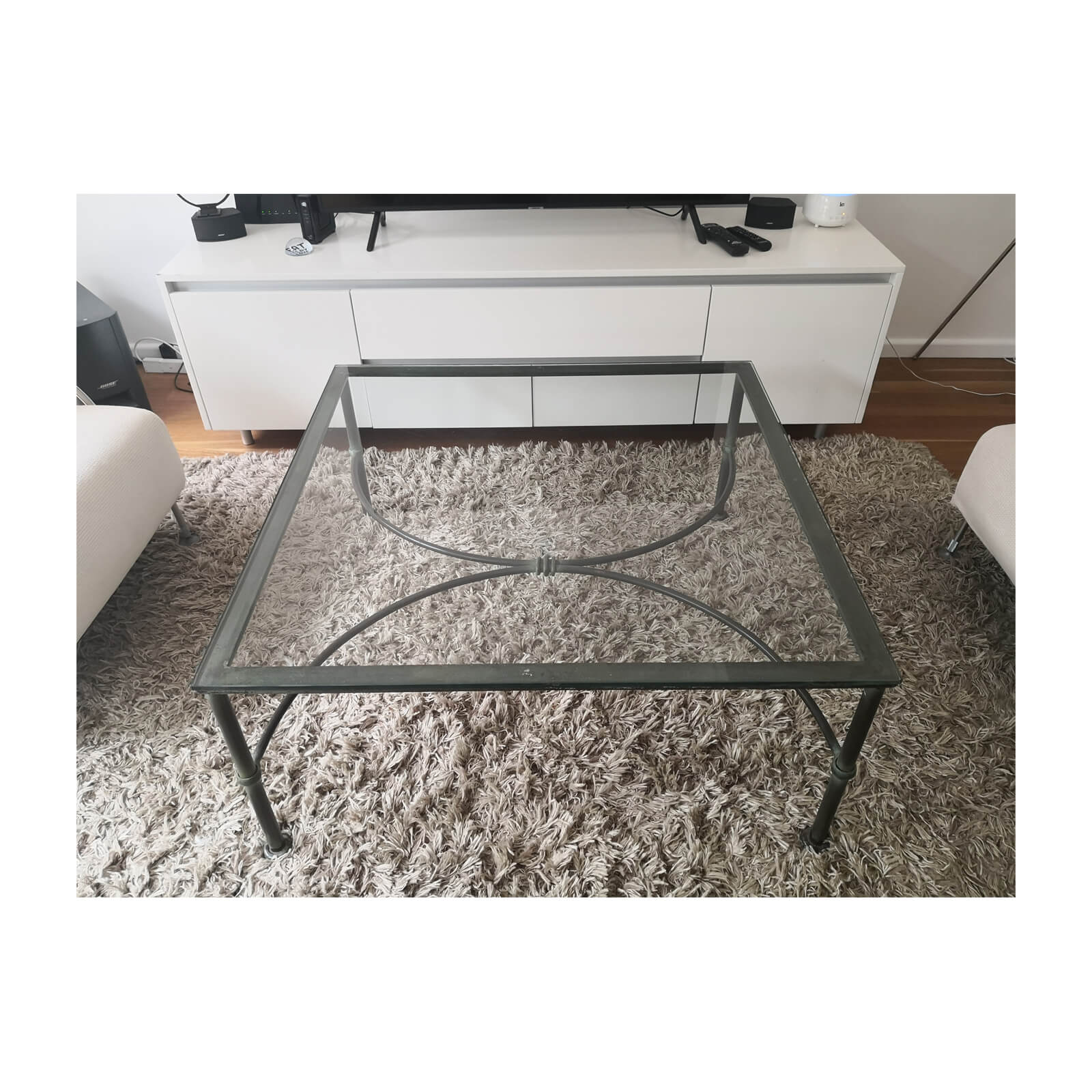 Wrought iron glass topped coffee table front on carpet